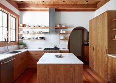 a kitchen with wooden cabinets and white counter tops, along with open shelving on the wall