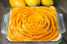 a glass dish filled with sliced oranges on top of a wooden table next to lemons