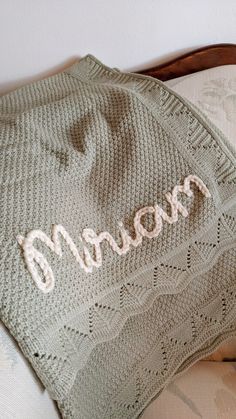 a crocheted blanket with the word mom written on it sitting on top of a bed