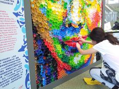 a woman kneeling down next to a colorful wall