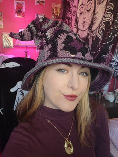 a woman wearing a purple hat with an animal on it's brim and gold necklace