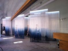 several people are walking in an open space with sheer curtains on the walls and floor