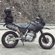 a motorcycle parked in a parking lot next to a brick wall and fenced area