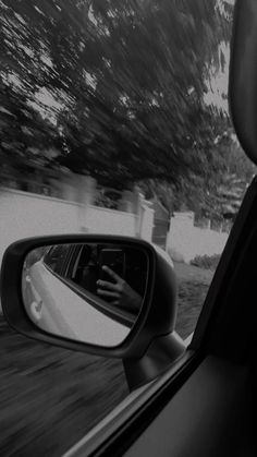 a person's hand is seen in the rear view mirror of a car as it drives