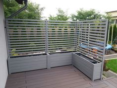 an outdoor garden with grey planters on the deck and fenced in area around it