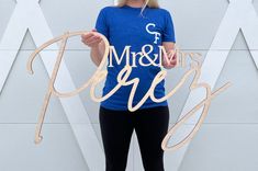 a woman standing in front of a wall holding up a sign