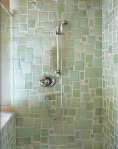 a shower head and hand held shower faucet in a bathroom with green tiles on the wall