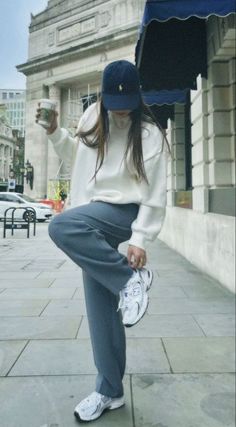 a woman sitting on the ground with an umbrella and holding a cup in her hand