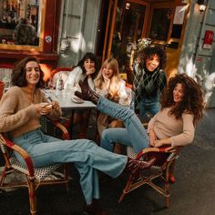 four women sitting at an outdoor table laughing