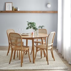 a dining room table with four chairs and a potted plant in the corner on top of it