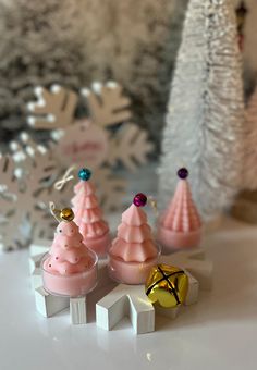 three small pink christmas trees are sitting on a table