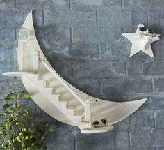 a wooden moon and star decoration on a brick wall next to a potted plant