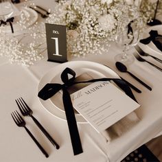 the table is set with black and white place settings, silverware, and napkins