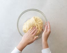 two hands reaching for a doughnut in a glass bowl