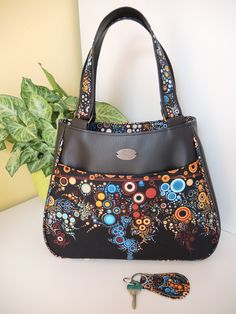 a handbag and keys on a table next to a potted plant