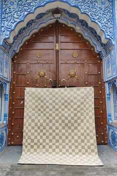 a large checkered rug is in front of an ornate wooden door