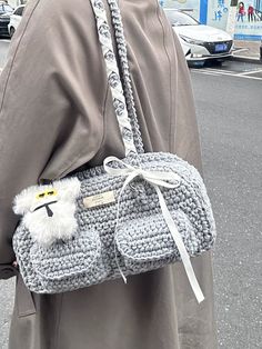 a woman is carrying a crocheted purse on the street