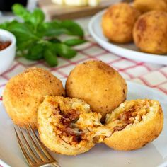 two muffins on a plate with a fork and bowl of sauce in the background