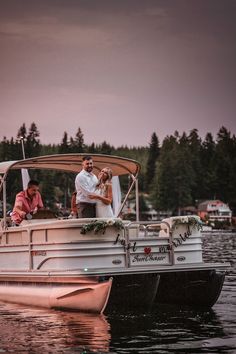 a bride and groom are riding on the back of a boat in the water at sunset