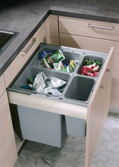 an open trash bin in the middle of a kitchen counter with food and drinks inside