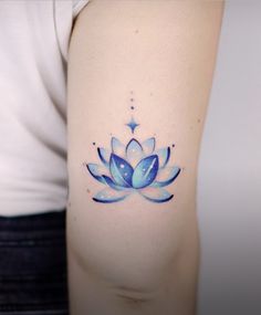 a woman's arm with a blue watercolor lotus tattoo on the left side