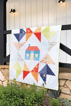 a quilt hanging on the side of a house