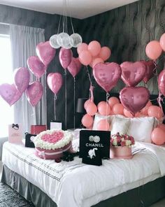 a bed with pink and white balloons hanging from the ceiling