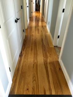 an empty hallway with wooden floors and white doors