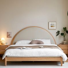 a bedroom with a bed, two nightstands and a potted plant in the corner