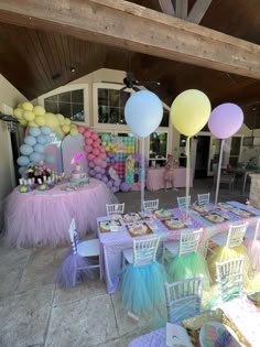 an outdoor party with balloons, cake and desserts on the tables in pastel colors