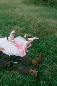 a man laying on the ground next to a woman in a white dress and shoes