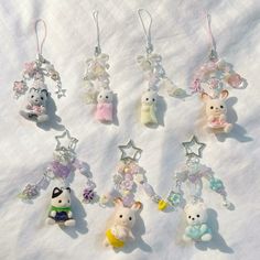 a group of small stuffed animals hanging from key chains on a white cloth covered surface