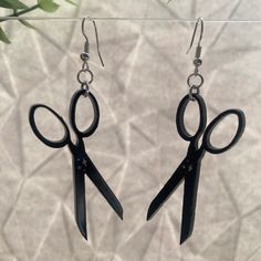 pair of black scissors dangling from silver earwires