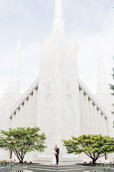 a man and woman standing in front of a large white building with tall spires