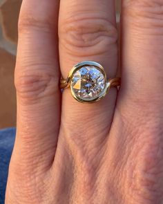 a woman's hand with a ring on it that has a diamond in the middle