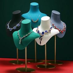 several necklaces are displayed on gold stands