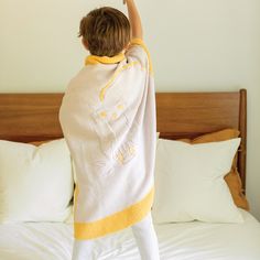 a little boy standing on top of a bed with his arms up in the air