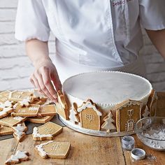 a woman is decorating gingerbread cookies on a table