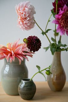 three vases with flowers in them sitting on a table