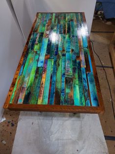 a table made out of stained glass and wooden planks is shown in the process of being worked on