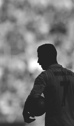 a black and white photo of a man holding a soccer ball in his hands with the words ronaldo on it