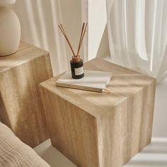 two wooden boxes with reeds in them sitting on a table next to a window