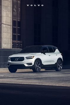 a white volvo suv parked in front of a building with the word volvo on it