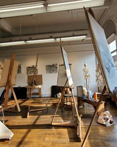 an artist's studio with easels and paintings on the floor in front of them