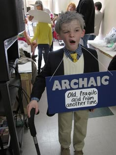 a young boy holding a sign that says archac old fragile and from another time