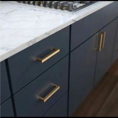 a kitchen with marble counter tops and brass pulls on the drawers in front of the sink