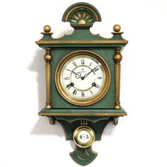 a green and gold clock mounted to the side of a wall