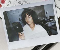 a polaroid photo of a woman holding a cell phone in front of her face