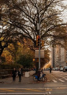 people walking and riding bikes on the sidewalk in front of traffic lights at an intersection