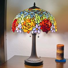 a stained glass lamp sitting on top of a wooden table next to a canister